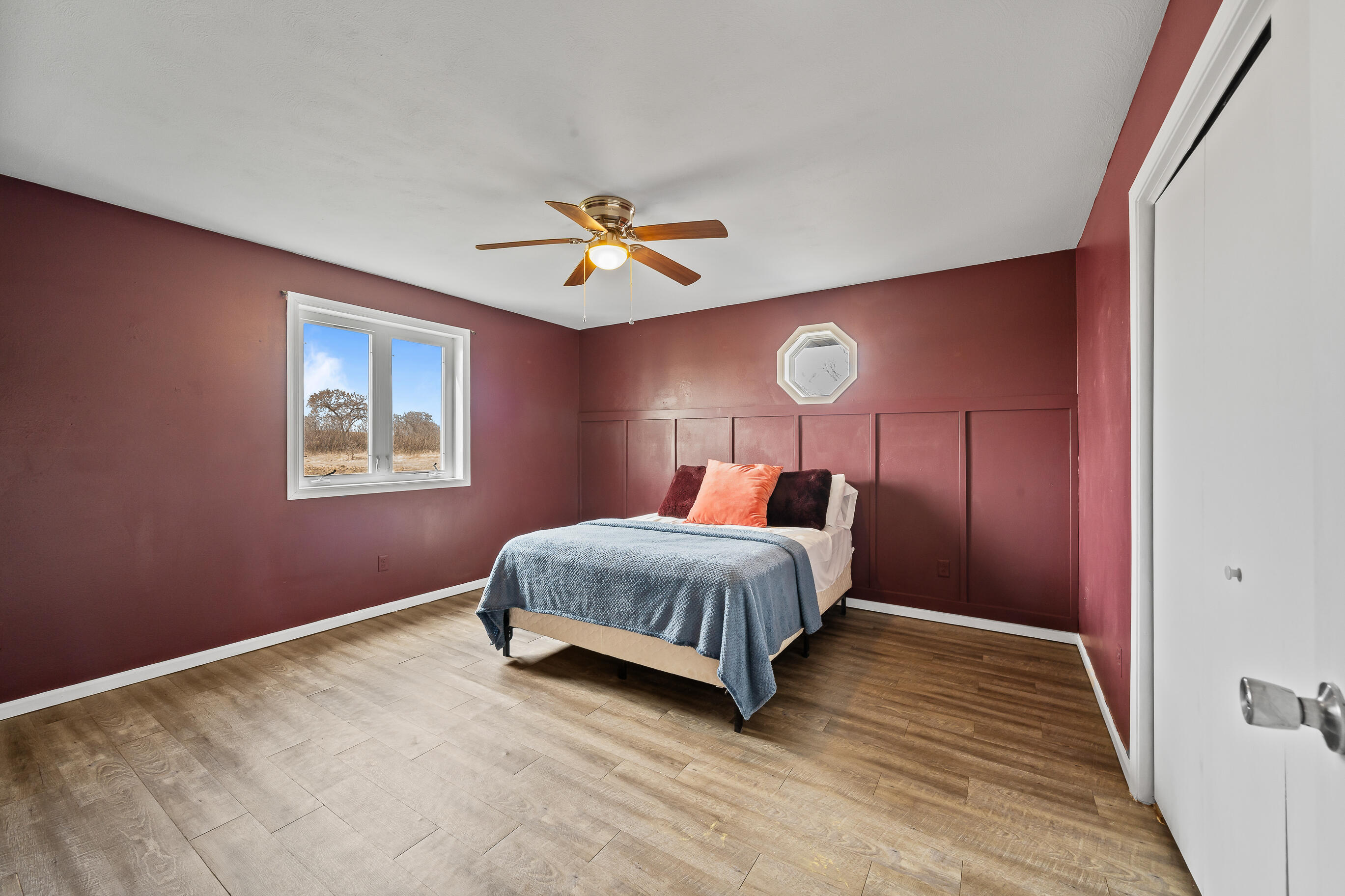 2212 Borg Road Delavan, WI 53115 - Photo 20 of 43 Primary bedroom with burgundy accent walls, board and batten wainscoting, ceiling fan, and octagonal accent window