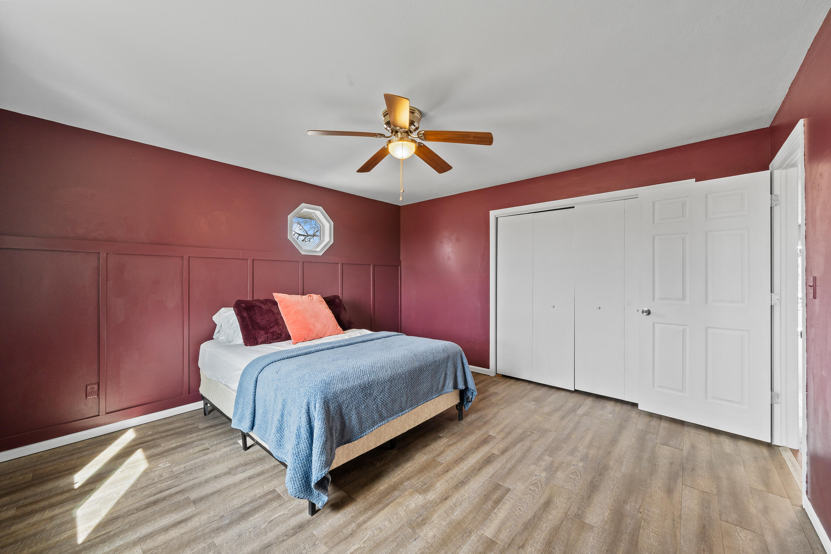 2212 Borg Road Delavan, WI 53115 - Photo 21 of 43 Primary bedroom with burgundy board and batten wainscoting, double closet doors, ceiling fan, and octagonal accent window