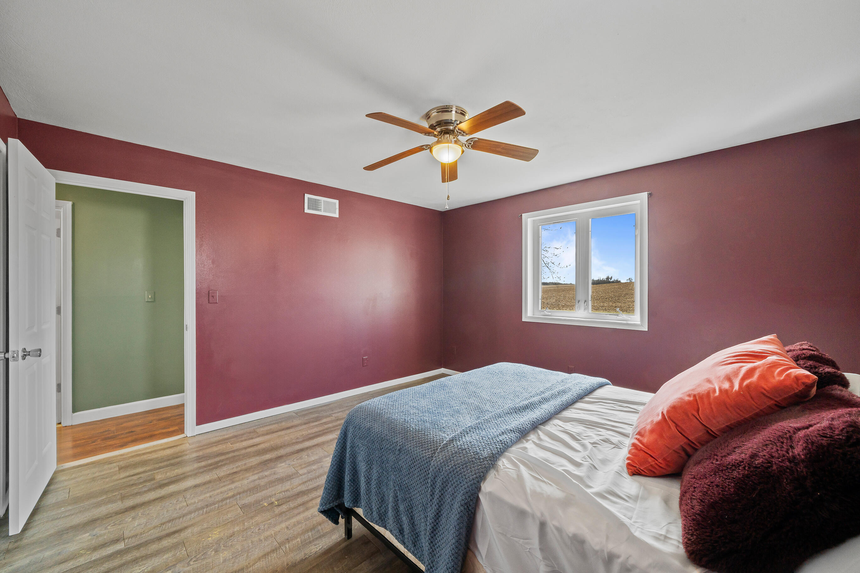 2212 Borg Road Delavan, WI 53115 - Photo 22 of 43 Primary bedroom with burgundy board and batten wainscoting, double closet doors, ceiling fan, and octagonal accent window