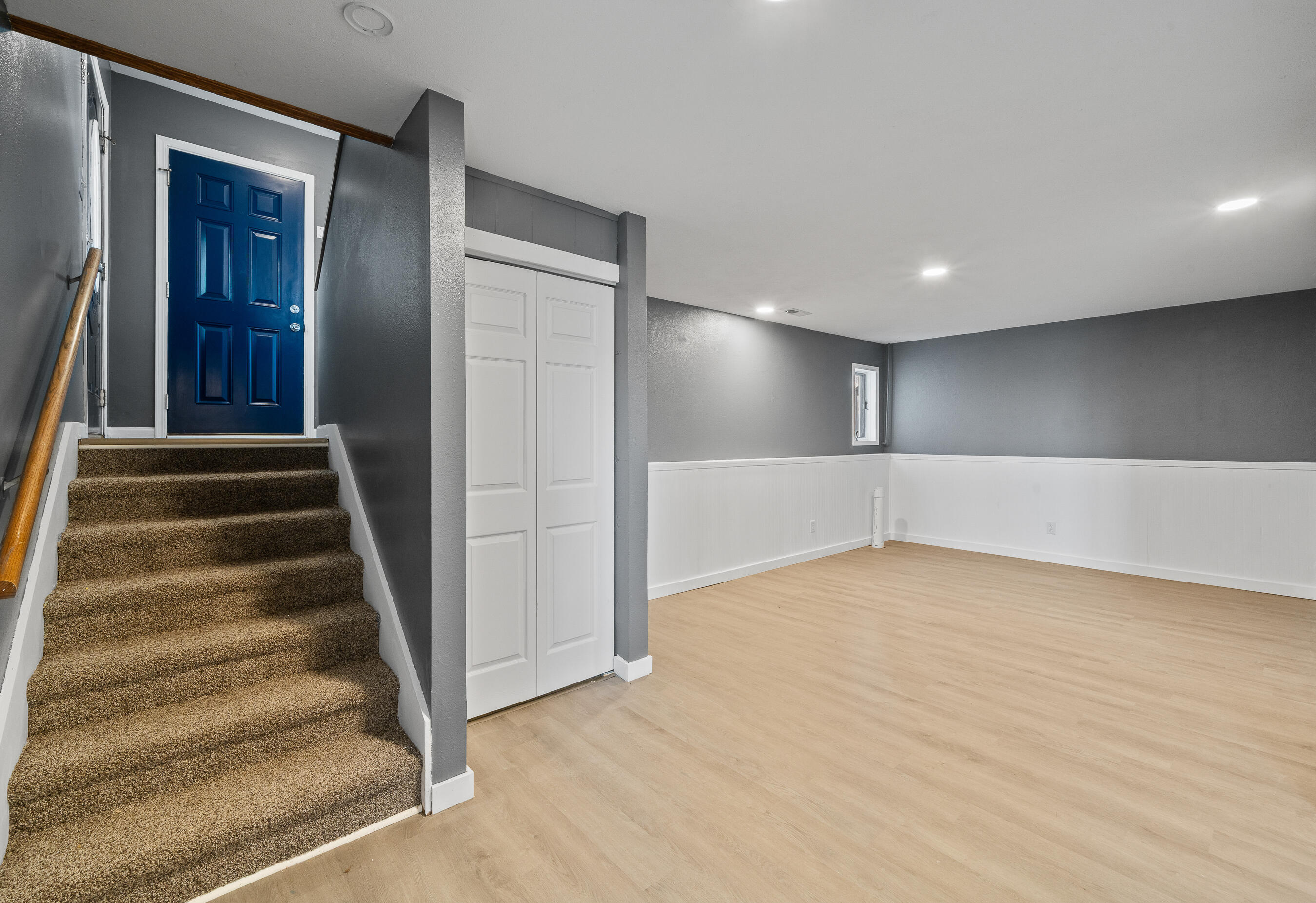 2212 Borg Road Delavan, WI 53115 - Photo 29 of 43 Finished lower level with carpeted staircase, closet storage, dark gray walls, white wainscoting, and vinyl plank flooring