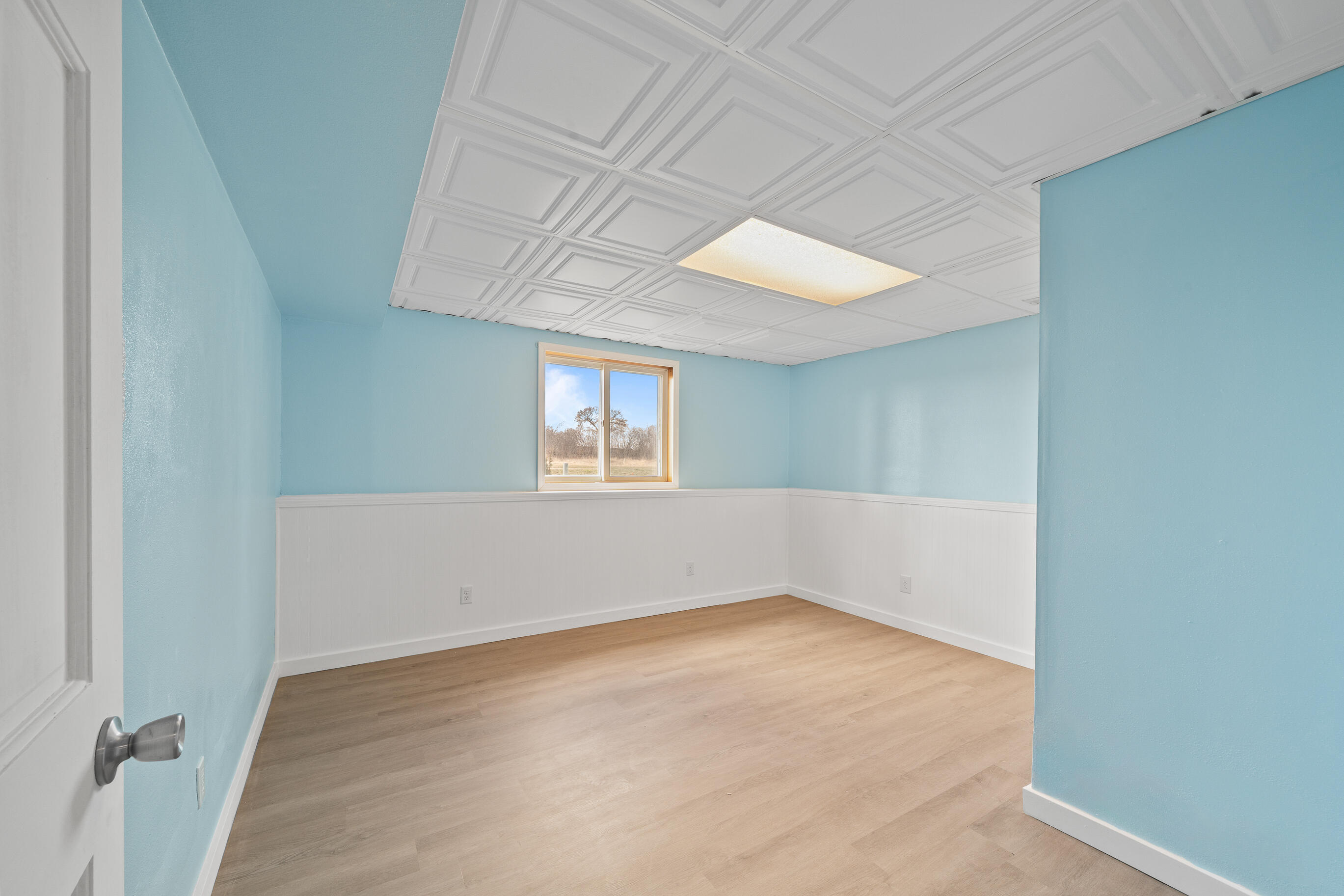 2212 Borg Road Delavan, WI 53115 - Photo 30 of 43 Lower level bedroom with light blue walls, white beadboard wainscoting, decorative ceiling tiles, vinyl plank flooring, and egress window