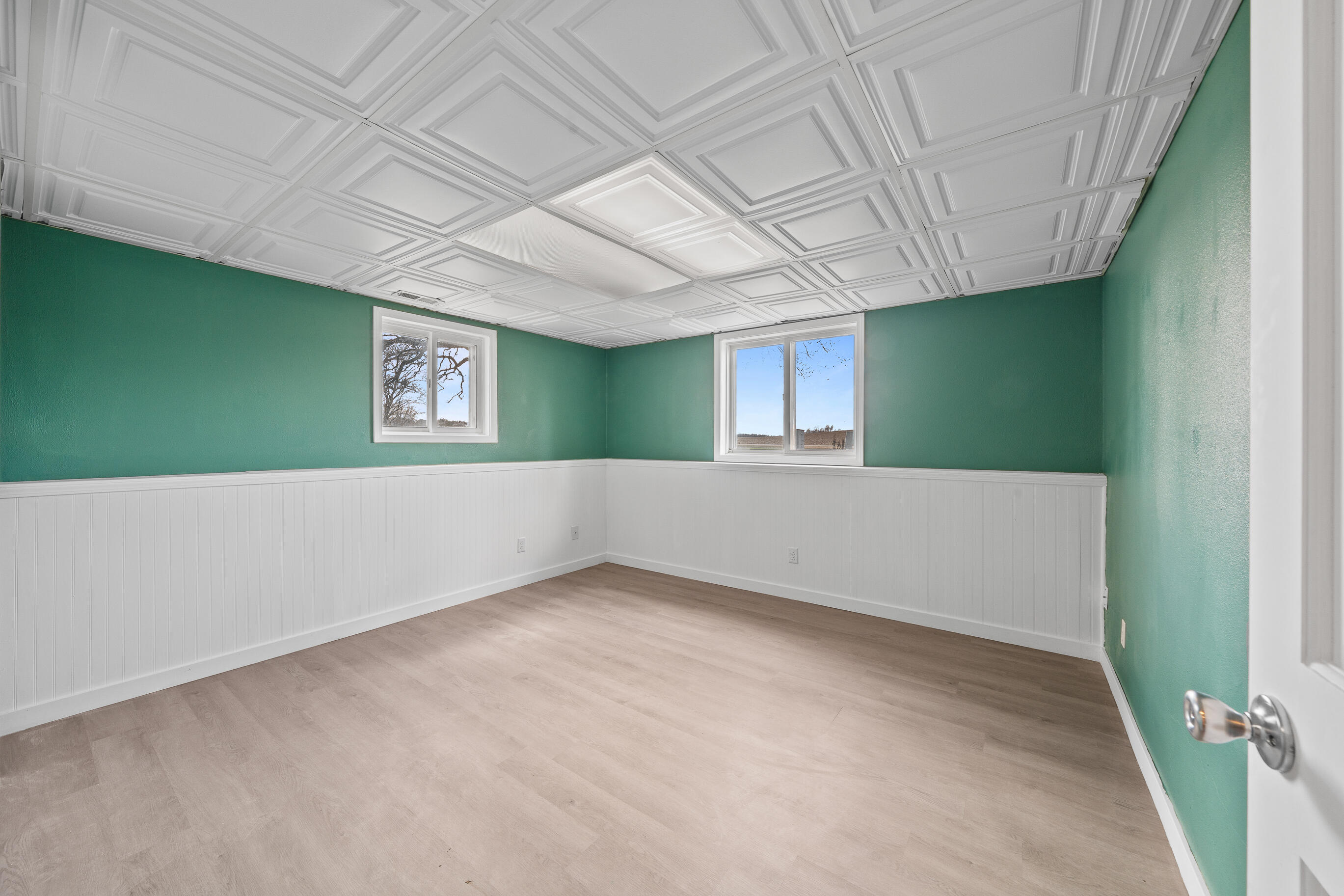 2212 Borg Road Delavan, WI 53115 - Photo 34 of 43 2nd Lower level bedroom with teal green walls, white beadboard wainscoting, decorative ceiling tiles, two windows with natural light, and vinyl plank flooring