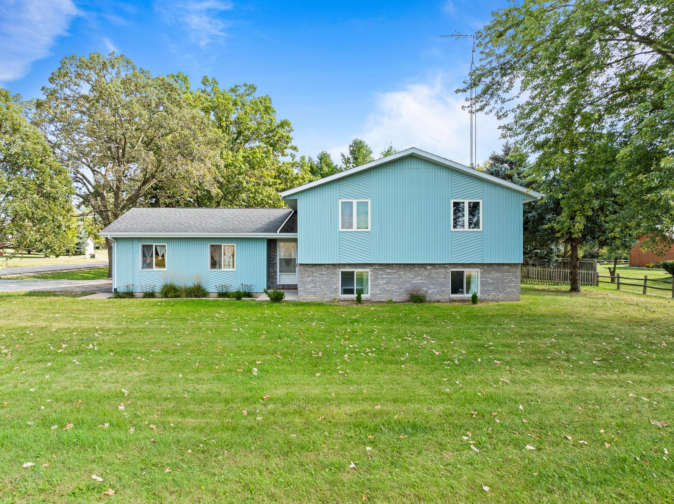 2212 Borg Road Delavan, WI 53115 - Photo 4 of 43 Full front view of this bi-level home featuring updated siding, stone-accented lower level, and a beautifully landscaped yard with mature trees.