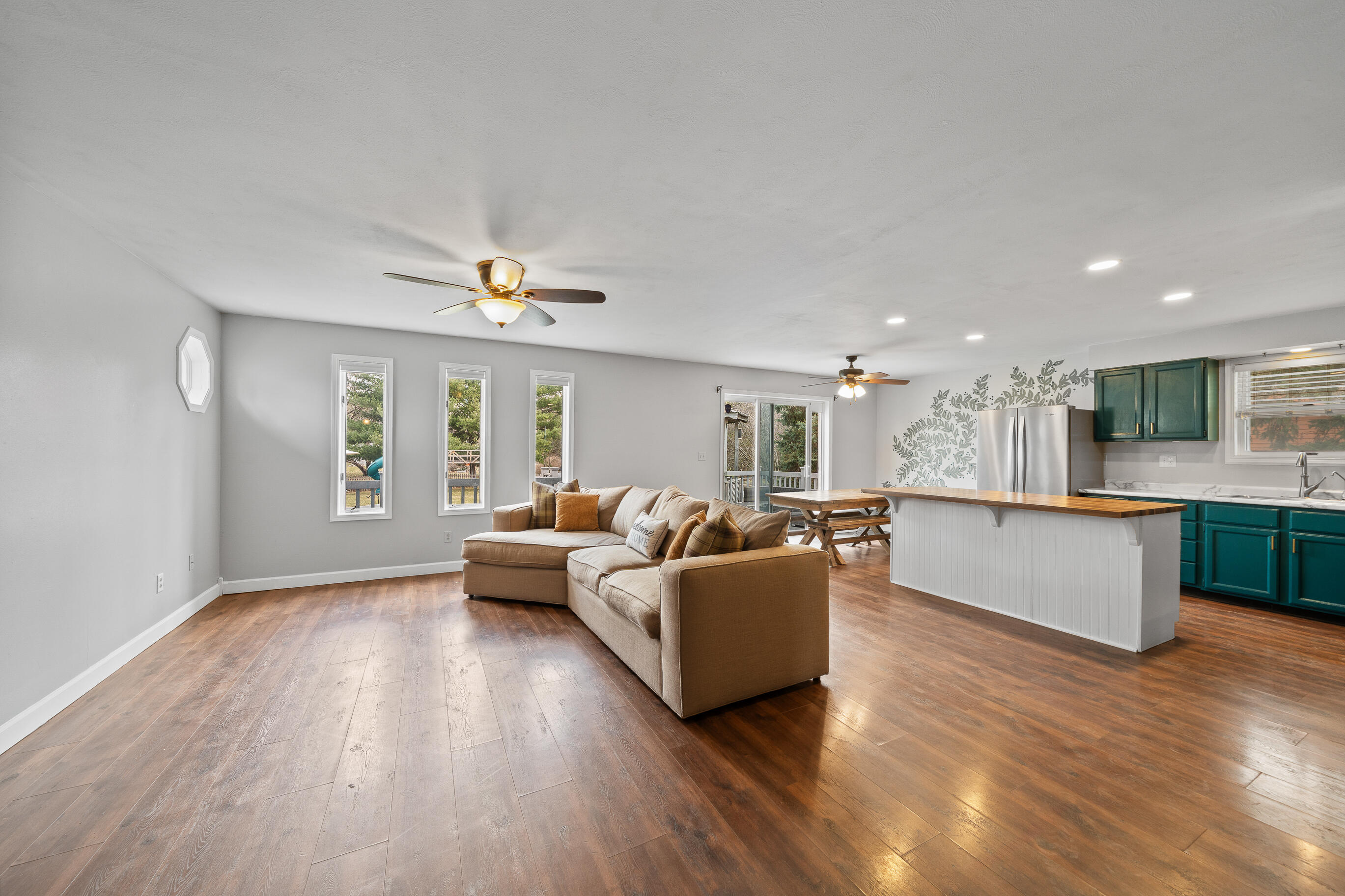 2212 Borg Road Delavan, WI 53115 - Photo 8 of 43 Spacious open-concept living room with hardwood floors, ceiling fan, and three windows overlooking the backyard; flows into kitchen and dining area
