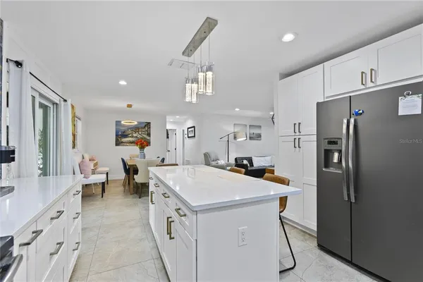 a kitchen with a sink a refrigerator and chairs