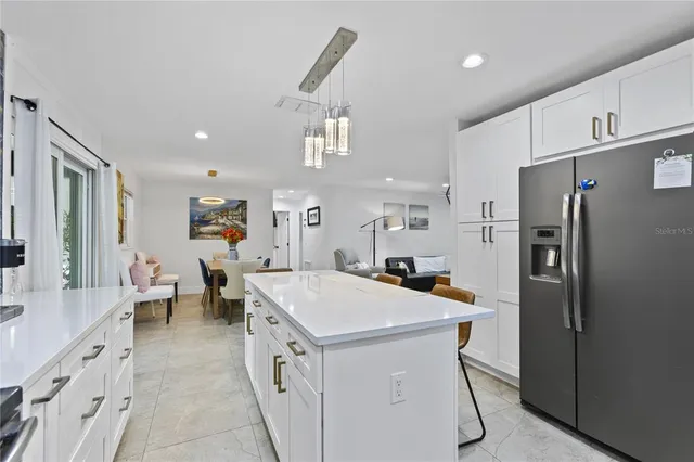 a kitchen with a sink a refrigerator and chairs
