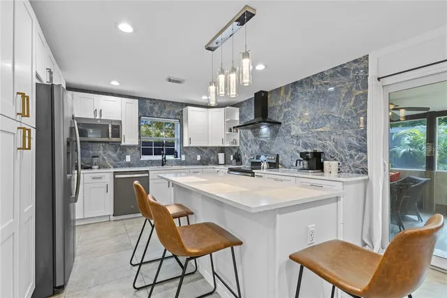 a kitchen with stainless steel appliances granite countertop a sink a stove a refrigerator cabinets and chairs