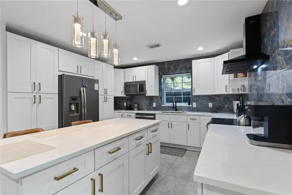 a kitchen with kitchen island white cabinets and refrigerator