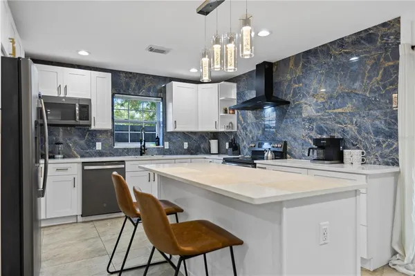 a kitchen with stainless steel appliances a sink a stove a refrigerator cabinets and a dining table