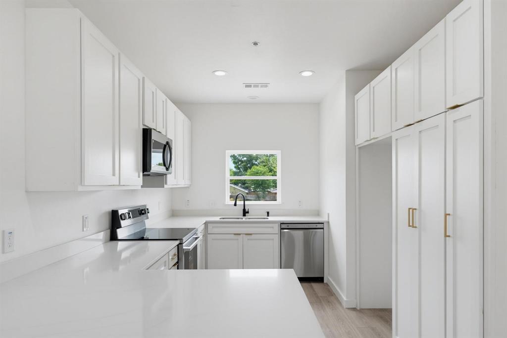 510 South O Connor Road Irving, TX 75060 - Photo 2 of 22 Modern kitchen featuring white shaker cabinetry, stainless steel appliances including a microwave, dishwasher, and range, a black gooseneck faucet, and light-toned countertops