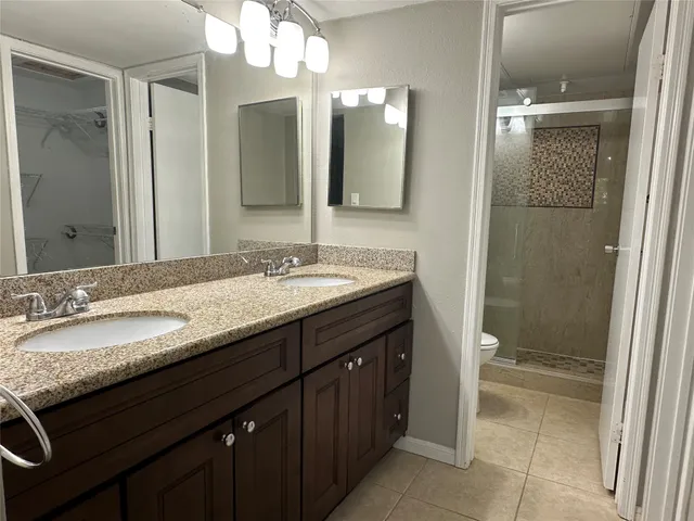 a bathroom with a granite countertop sink a large mirror and a shower
