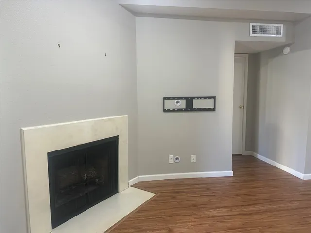 a view of a livingroom with wooden floor and a fireplace