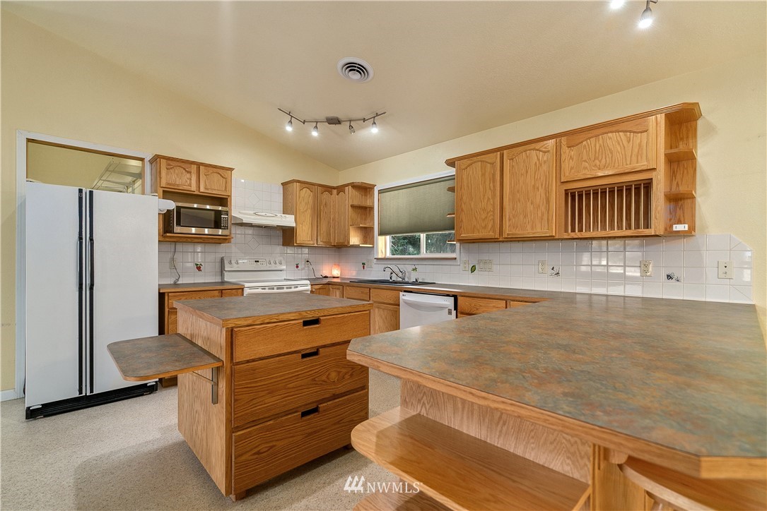 7625 187th Avenue Southwest Rochester, WA 98579 - Photo 7 of 38 a kitchen with granite countertop a refrigerator and a stove top oven