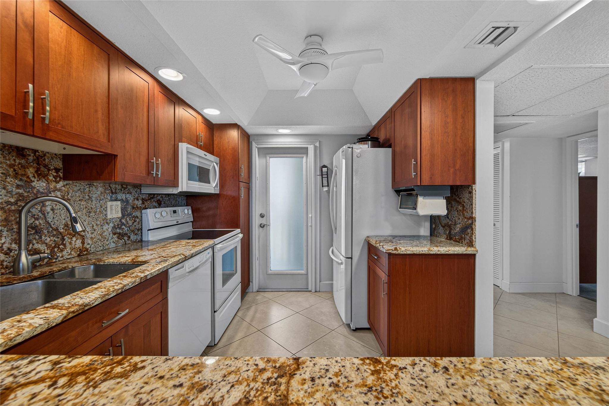 3150 Northeast 48th Court, Unit 414 Lighthouse Point, FL 33064 - Photo 11 of 33 a kitchen with stainless steel appliances granite countertop a refrigerator a sink dishwasher a stove and white cabinets with wooden floor