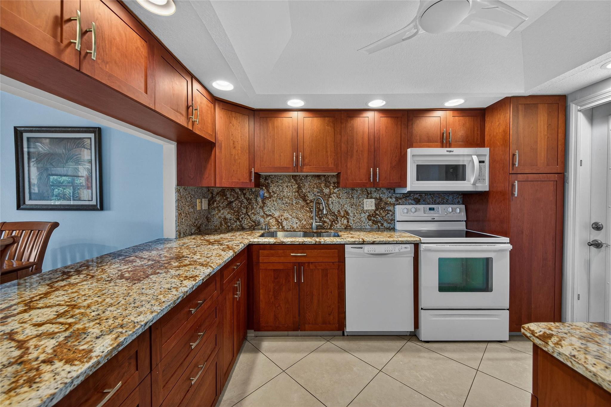 3150 Northeast 48th Court, Unit 414 Lighthouse Point, FL 33064 - Photo 12 of 33 a kitchen with stainless steel appliances granite countertop wooden cabinets a stove top oven a sink and dishwasher