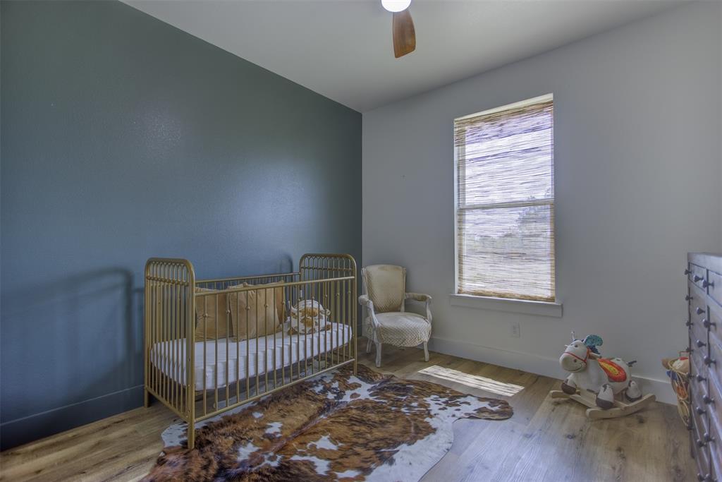 550 Capstone Rdg Road Santo, TX 76472 - Photo 23 of 40 Bedroom with baseboards, wood finished floors, a ceiling fan, and a crib