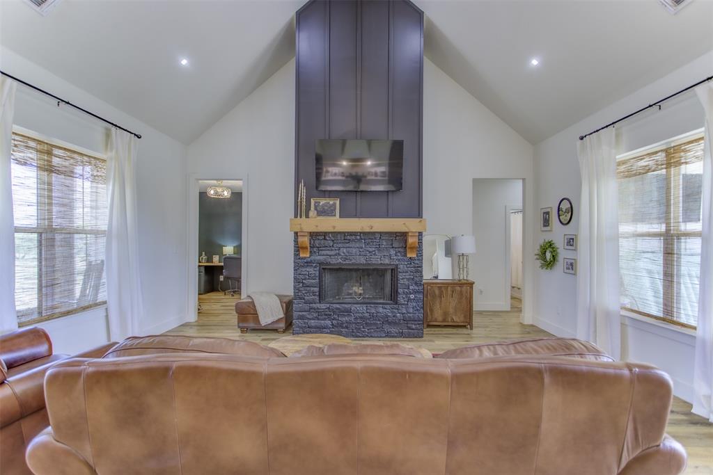 550 Capstone Rdg Road Santo, TX 76472 - Photo 26 of 40 Living area with high vaulted ceiling, wood finished floors, baseboards, and a stone fireplace