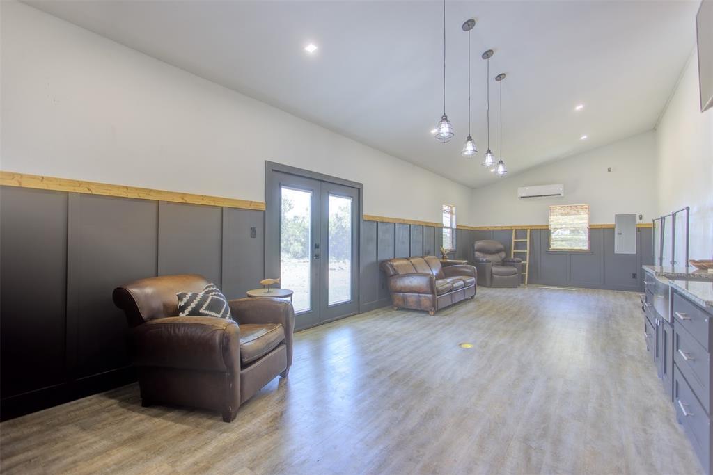 550 Capstone Rdg Road Santo, TX 76472 - Photo 33 of 40 Living room featuring french doors, a wall mounted air conditioner, a decorative wall, wainscoting, and light wood-type flooring