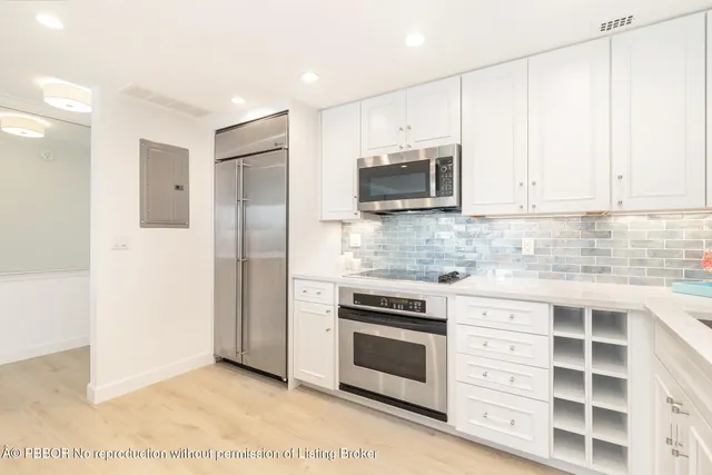 a kitchen with cabinets stainless steel appliances and wooden floor