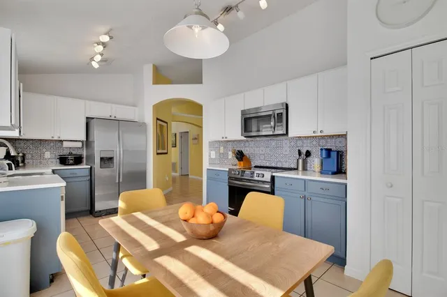 a kitchen with stainless steel appliances a sink a stove a refrigerator cabinets and dining table