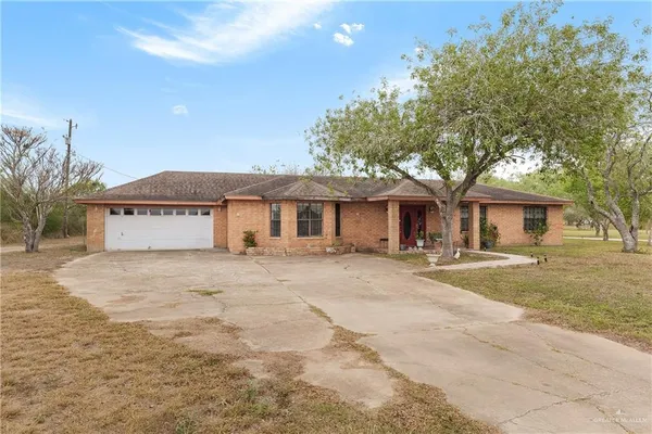 a front view of a house with a garden and tree