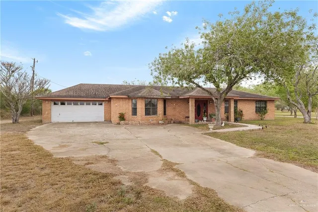 a front view of a house with a garden and tree