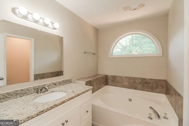 a bathroom with a tub sink and mirror