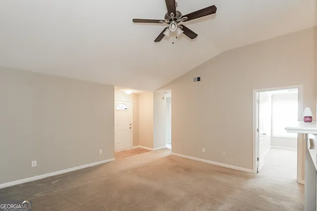 an empty room with a ceiling fan and carpet