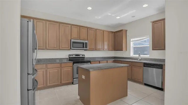 a kitchen with stainless steel appliances granite countertop a stove a sink and a microwave