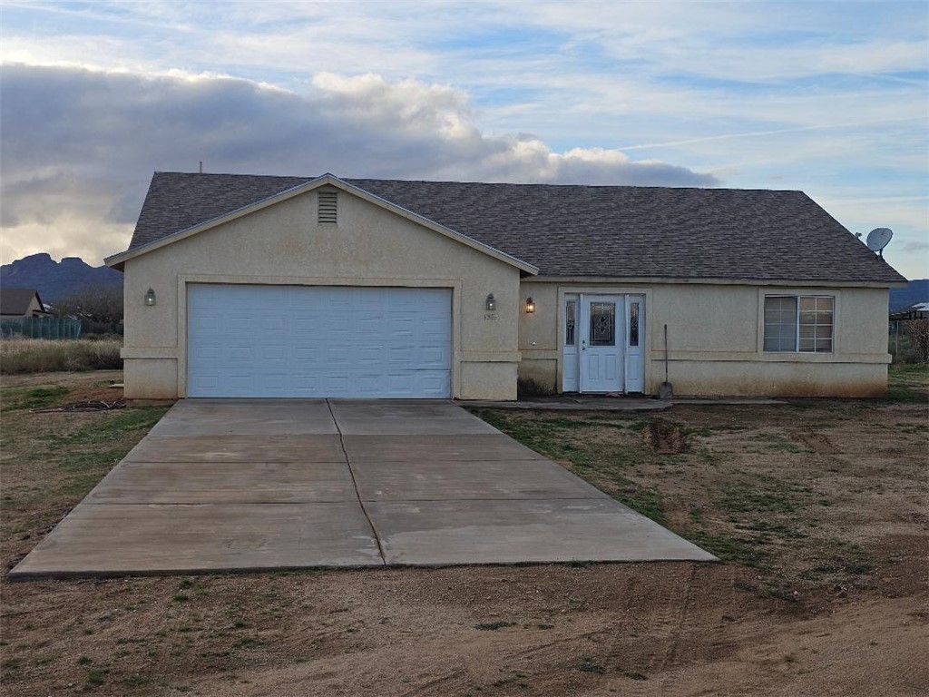 1069 Teddy Roosevelt Road Golden Valley, AZ 86413 - Photo 1 of 24 Ranch-style home with stucco siding, a shingled roof, driveway, and an attached garage