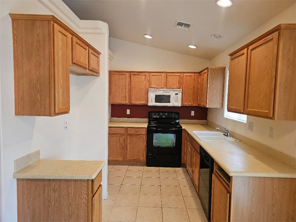 1069 Teddy Roosevelt Road Golden Valley, AZ 86413 - Photo 3 of 24 Kitchen featuring black appliances, light countertops, brown cabinets, vaulted ceiling, and light tile patterned floors