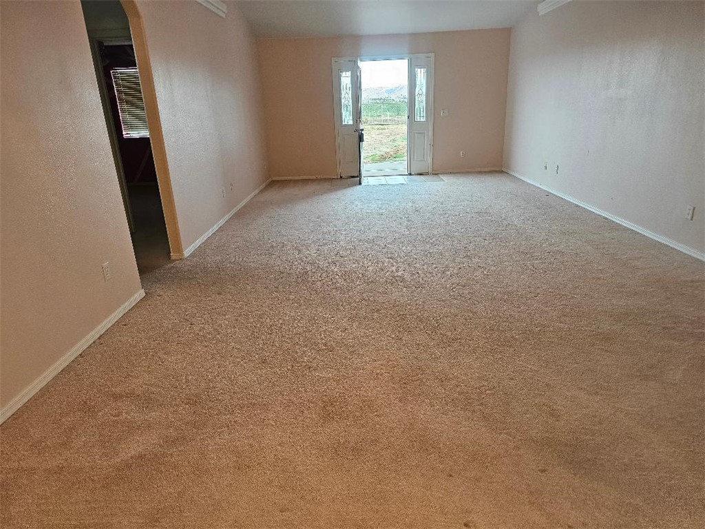 1069 Teddy Roosevelt Road Golden Valley, AZ 86413 - Photo 4 of 24 Empty room featuring arched walkways, carpet flooring, and a textured wall