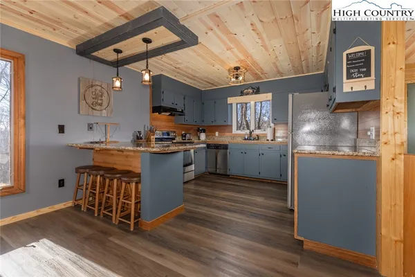 a kitchen with stainless steel appliances granite countertop a stove a sink dishwasher and a refrigerator with wooden floor