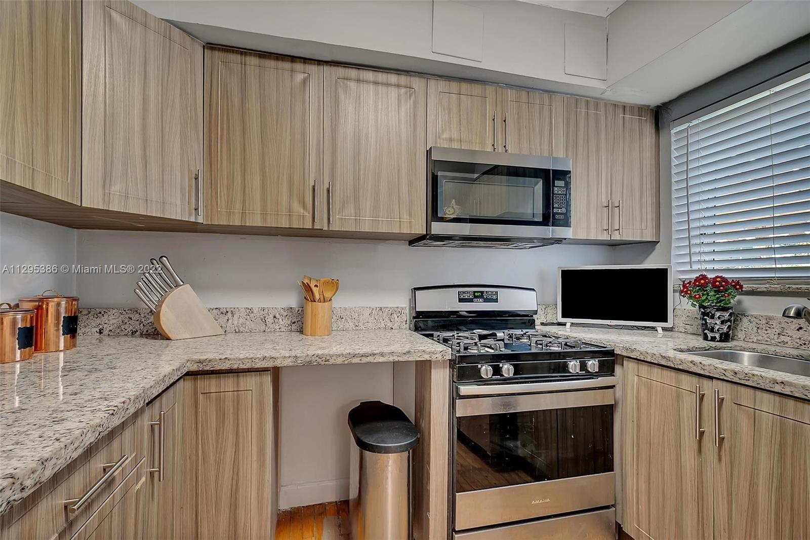 1242 Southwest 13th Avenue Miami, FL 33135 - Photo 8 of 42 a kitchen with granite countertop a sink stove and microwave