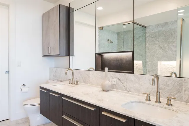 a bathroom with a granite countertop sink a toilet and mirror