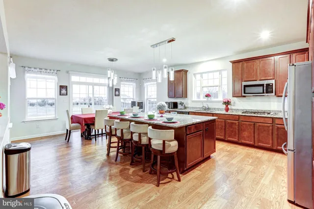 a kitchen with stainless steel appliances granite countertop a sink a stove and a wooden cabinets