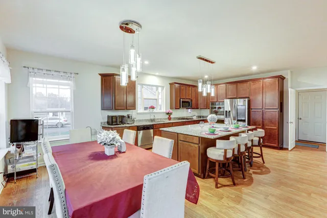 a kitchen with a stove a sink dishwasher a dining table and chairs with wooden floor