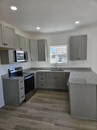 a kitchen with granite countertop a sink cabinets and stainless steel appliances