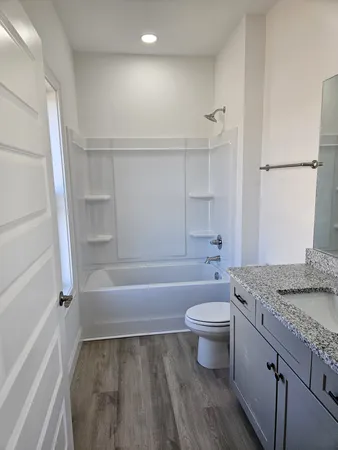 a bathroom with a granite countertop sink a toilet and shower