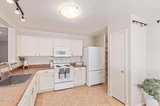 a kitchen with white cabinets and white appliances