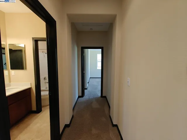 a view of a hallway with wooden floor and a bathroom