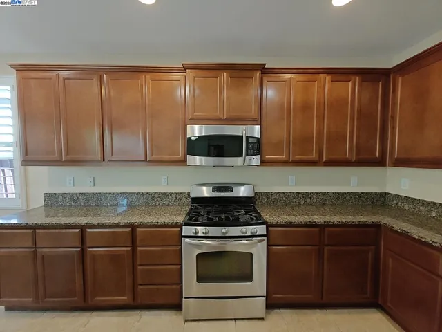 a kitchen with granite countertop stainless steel appliances a stove a sink and a microwave
