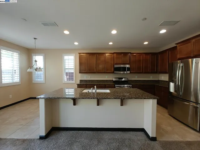 a kitchen with kitchen island granite countertop a sink stainless steel appliances and cabinets