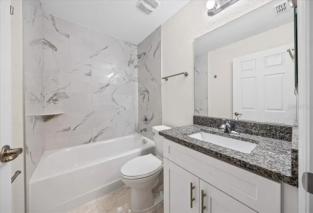 a bathroom with a granite countertop sink a toilet and a bathtub