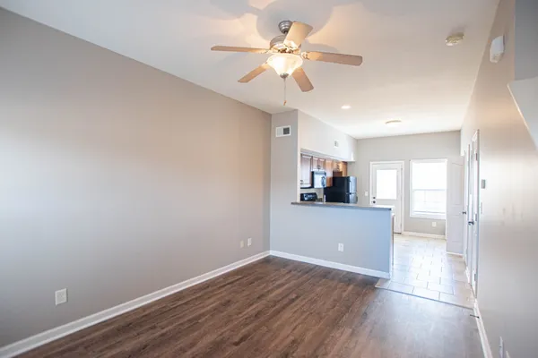 a view of a room with wooden floor and a ceiling fan