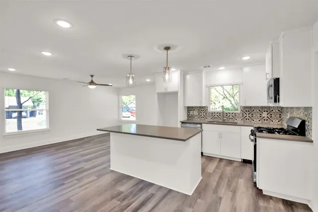 a kitchen with stainless steel appliances granite countertop wooden floors a stove a sink and a refrigerator