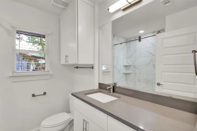 a bathroom with a granite countertop sink toilet and shower