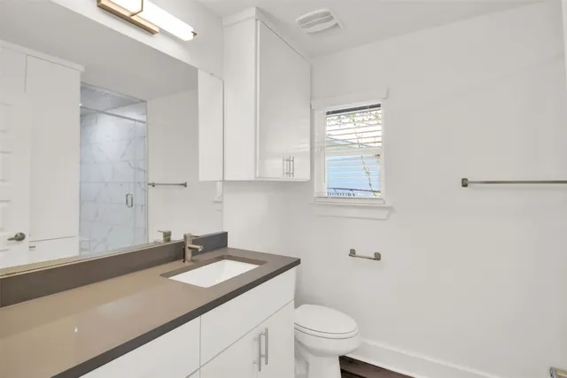 a bathroom with a granite countertop sink toilet and mirror