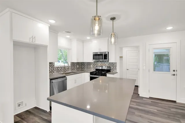 a large kitchen with kitchen island a stove a sink a center island and wooden floor