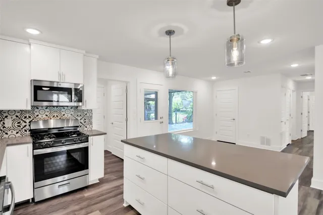 a kitchen with stainless steel appliances granite countertop a stove a sink and a white cabinets